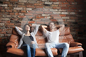 Young happy couple relaxing on comfortable leather couch at home