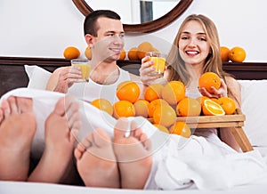 Young happy couple with ripe oranges and freshly juice