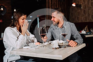 Young happy couple romantic date drink glass of red wine at restaurant, celebrating valentine day