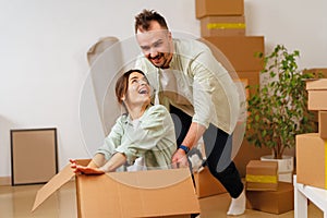 Young happy couple in room with moving boxes at new home