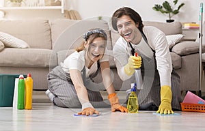 Young happy couple in rubber gloves cleaning floor in their apartment photo