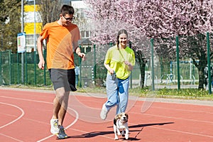 Young happy couple running with a dog