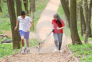 Young happy couple running with a dog