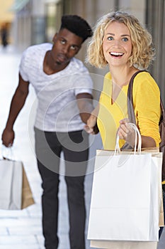 young happy couple with shopping bags in city