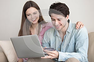 Young happy couple shopping online via laptop with credit card
