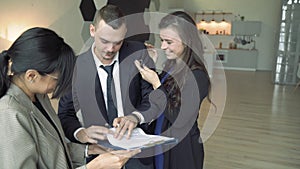 Young happy couple signing a lease or purchase and receiving keys from a new apartment or house