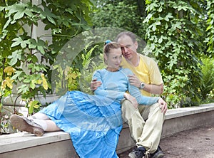 Young happy couple sits in the arbour twined greens