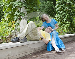 Young happy couple sits in the arbour twined greens