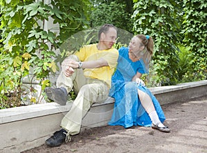 Young happy couple sits in the arbour twined greens