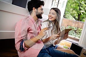 Young happy couple sitting on the floor with laptop booking holidays