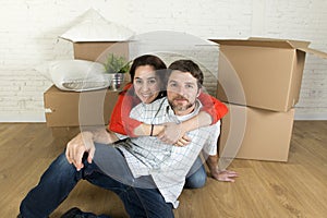 Young happy couple sitting on floor together celebrating moving in new flat house or apartment