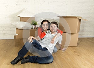 Young happy couple sitting on floor together celebrating moving in new flat house or apartment