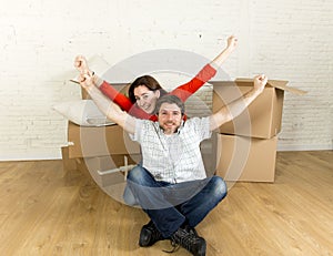 Young happy couple sitting on floor together celebrating moving in new flat house or apartment