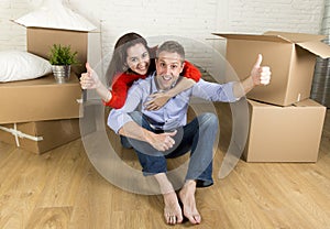 Young happy couple sitting on floor together celebrating moving in new flat house or apartment