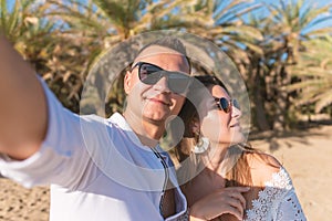 Young happy couple taking selfie on a palm beach . Summer vacations concept