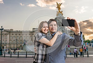 Young happy couple is taking selfie photo near Buckingham palace.