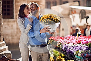 Young happy couple in their honeymoon in italy, toscana, europe. Man is buying a bucket of flowers for his girlfriend
