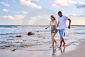 Young happy couple walking on the beach holding hands, copy space