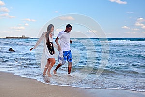 Young happy couple walking on the beach holding hands, copy space