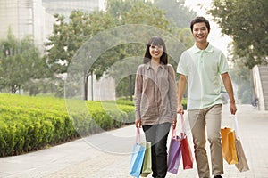 Young happy couple walking with colorful shopping bags in hands in Beijing, China