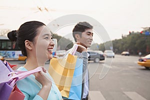 Young happy couple walking down the street with colorful shopping bags in Beijing