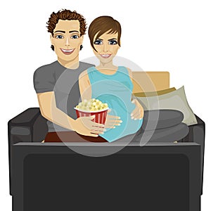 Young happy couple watching movie at home sitting with popcorn on sofa
