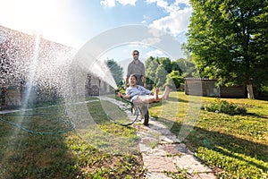 Young happy couple watering garden, a girl with a hose in hand on a trolley, spring and summer concept, eco-friendly lifestyle