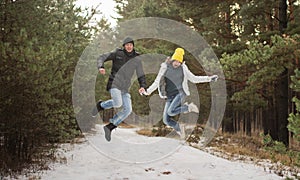 Young happy Couple in Winter Park jumping. Family Outdoors. love