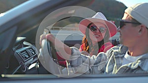 Young happy couple woman and man talking in convertible car while driving.