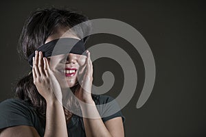 Young happy and cute blindfolded Asian Korean teenager girl excited playing dangerous internet viral challenge on dark