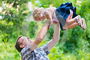 Young happy dad playfully tosses his little daughter