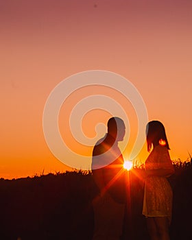 Young happy engaged couple silhouetted at sunset