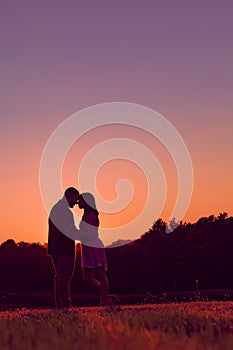 Young happy engaged couple silhouetted at sunset