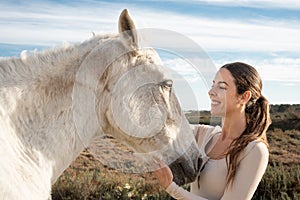 Young happy equestrian female posing and having fun with her horse near a farm