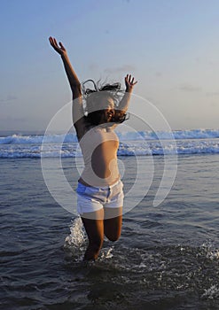 Young happy and excited Asian woman having fun enjoying playful and free at sunset beach in tourism vacation