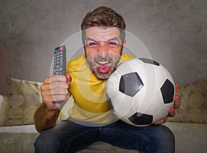 Young happy and excited man watching European football game on TV celebrating goal on couch screaming spastic gesturing crazy