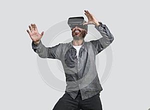 Young happy and excited man wearing virtual reality VR goggles headset experimenting 3d illusion playing video game touching