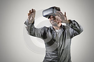 Young happy and excited man wearing virtual reality VR goggles headset experimenting 3d illusion playing video game touching