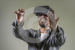 Young happy and excited man wearing virtual reality VR goggles headset experimenting 3d illusion playing video game touching