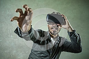 Young happy and excited man wearing virtual reality VR goggles headset experimenting 3d illusion playing video game touching