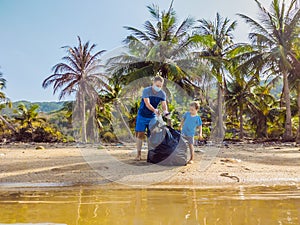 Young happy family activists collecting plastic waste on beach. Dad and son volunteers clean up garbage. Environmental