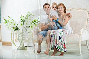 Young happy family with baby boy on couch at home