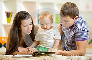 Young happy family with baby boy reading children