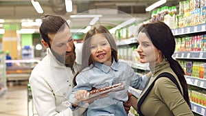 Young happy family buy sausage in the supermarket. Slow motion.