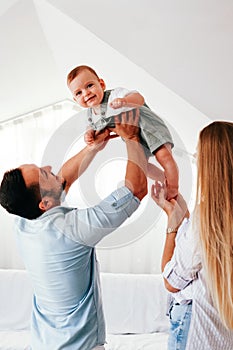 Young happy family. Careful young Caucasian parents playing with their little cute baby boy.