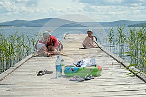 A young happy family with a child is resting near the lake.