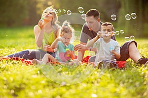 Happy family with children blow soap bubbles outdoor