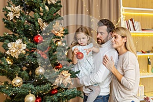 A young happy family decorates a Christmas tree for the Christmas holidays