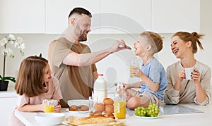 Young happy family eating morning breakfast together at home