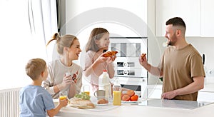 Young happy family eating morning breakfast together at home